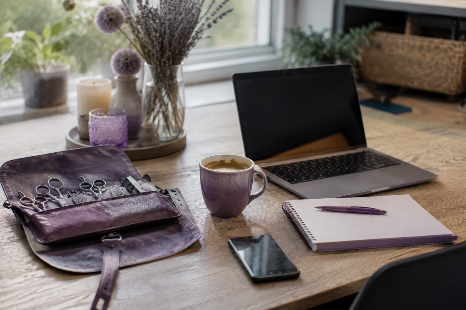 Stilleven van een kappersschaar in een leren etui naast een laptop en een kop koffie op een werkplek